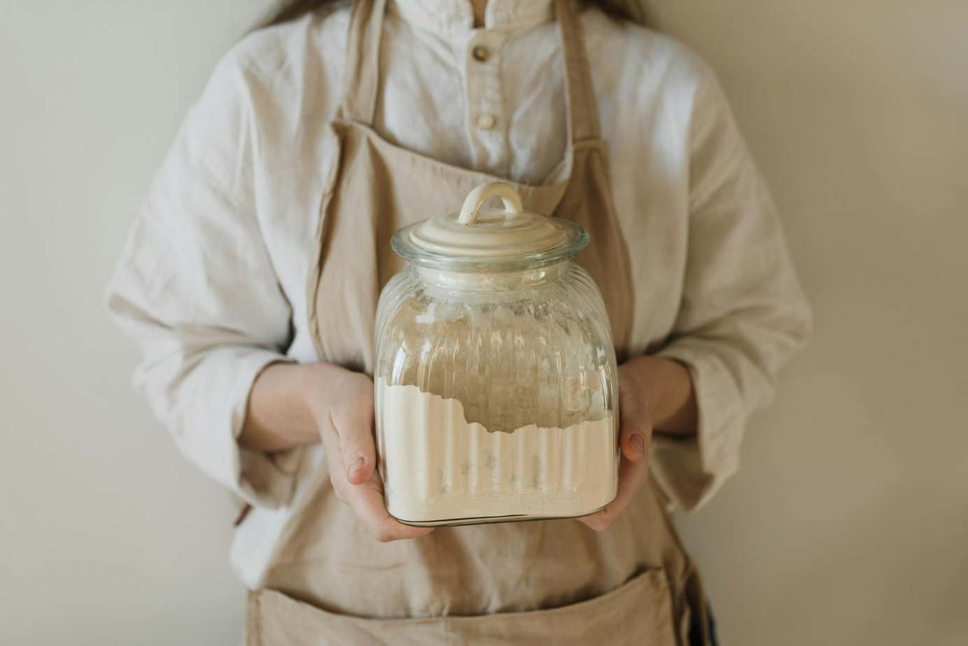 Person holding a glass jar filled with flour for long-term storage.