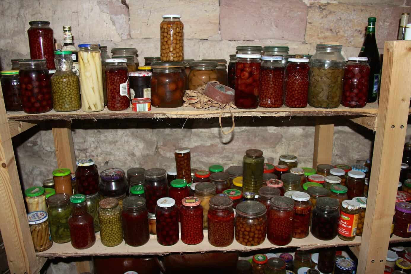 Shelves of preserved food jars showing rotation and maintenance for long term food storage in basement.