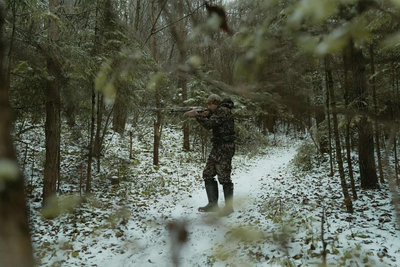 Hunter tracking game in a snowy winter forest, demonstrating how to hunt for survival in winter.
