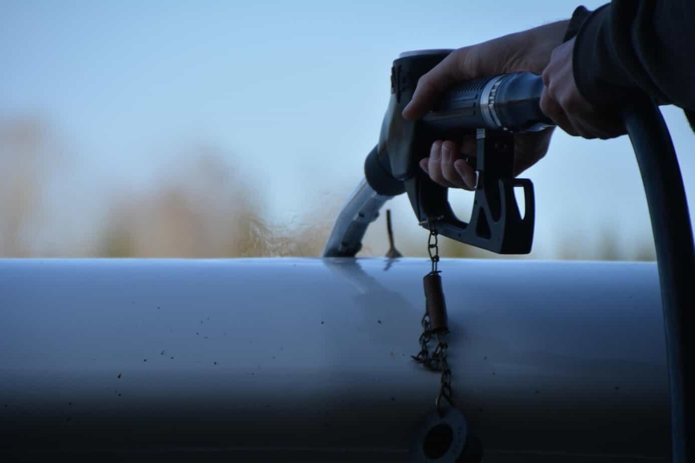 Person filling a fuel tank while preparing for fuel rationing and emergency fuel storage