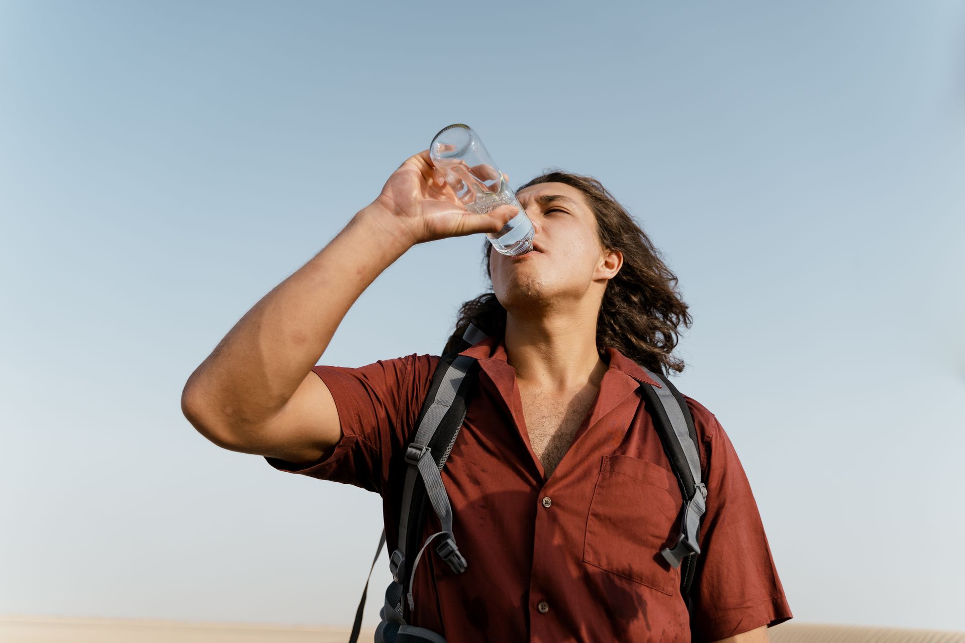Man drinking water from a bottle outdoors, illustrating how long you can go without water in hot, dry conditions