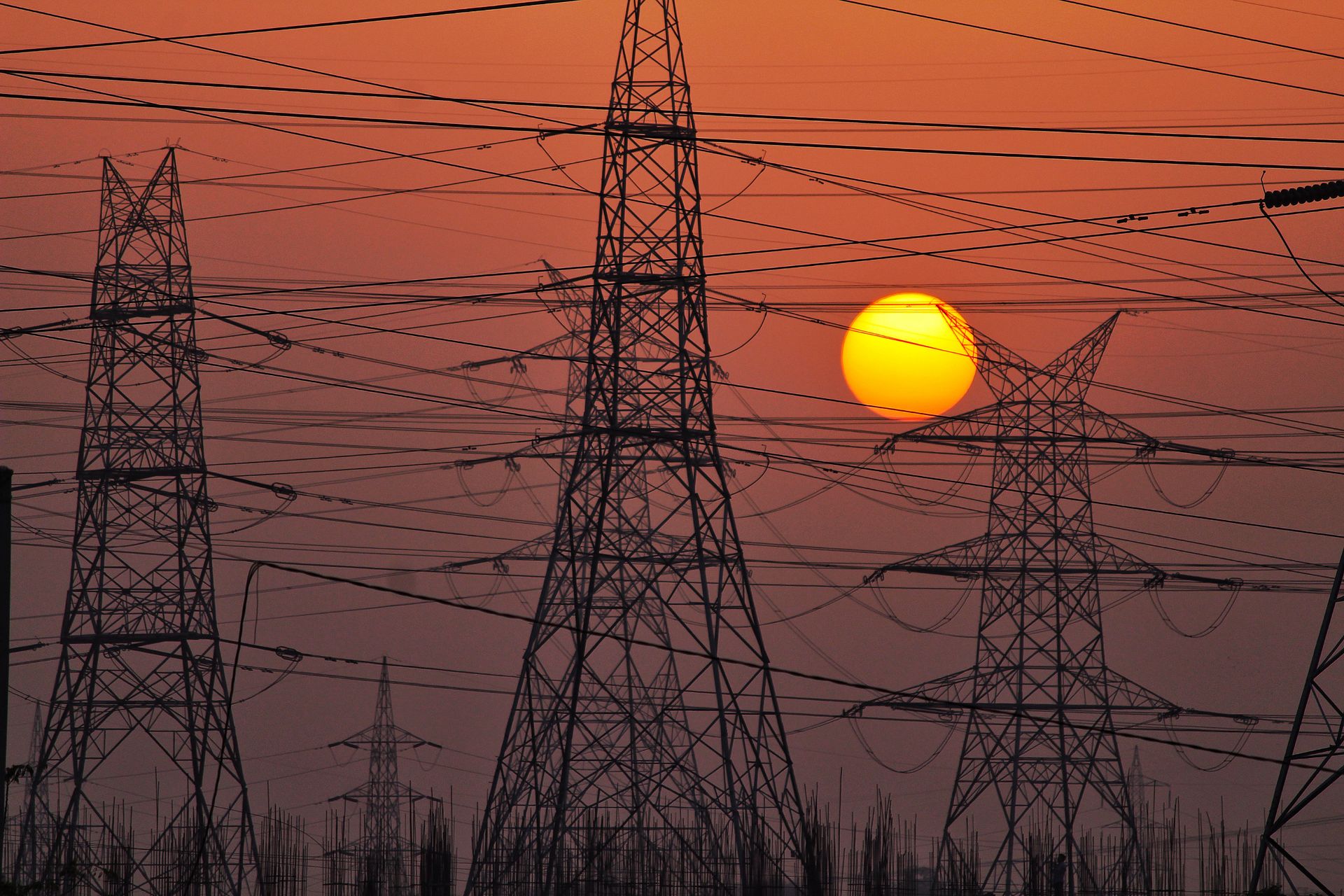 Silhouetted high voltage transmission towers and power lines at sunset, where power grid cascading failures spread