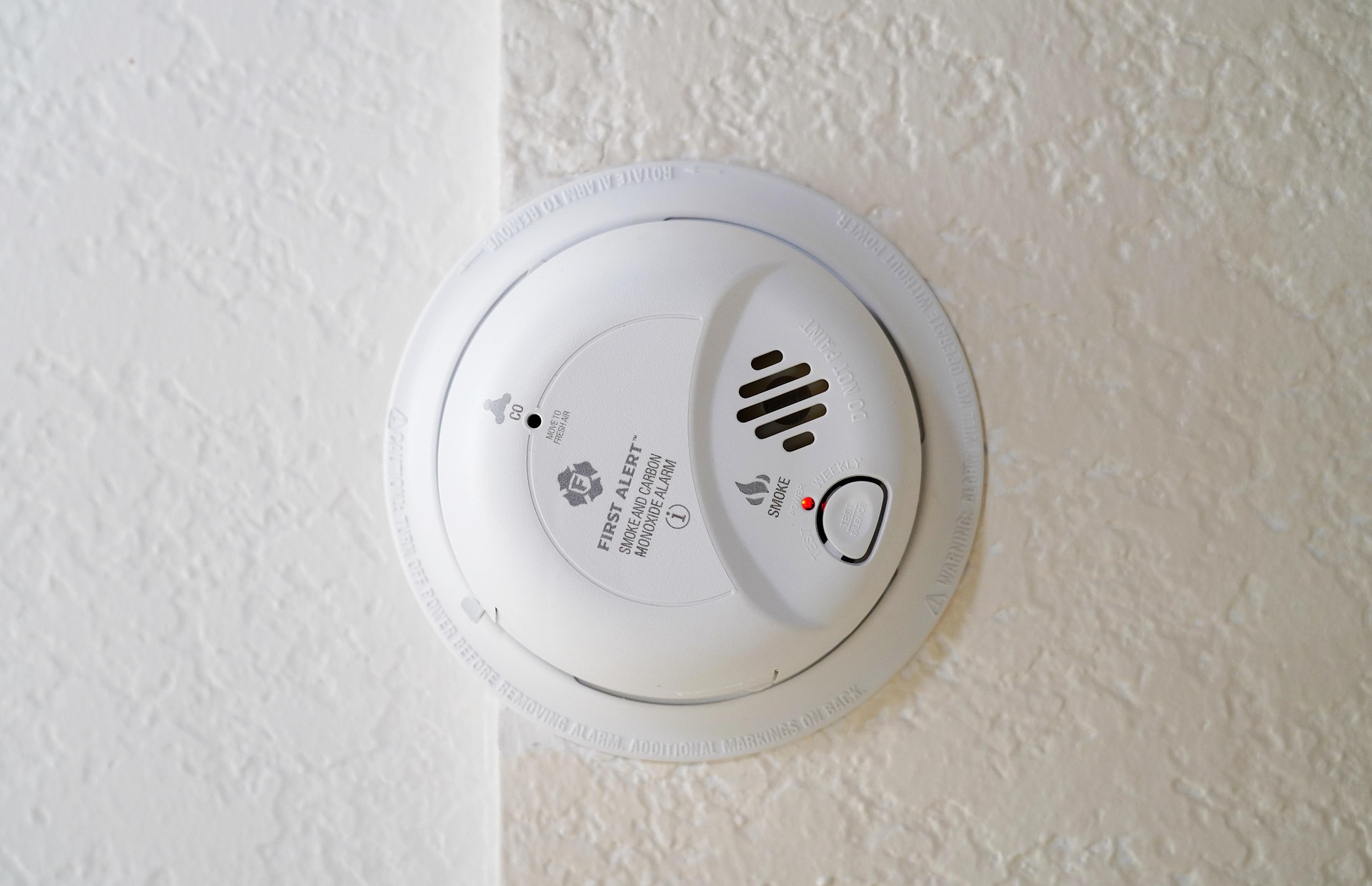 White smoke and carbon monoxide alarm mounted on a textured ceiling to reduce the risk of carbon monoxide poisoning